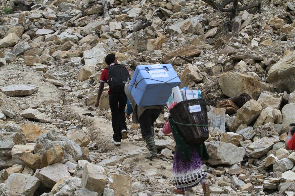 Health care workers carry UNICEF-provided vaccines on difficult terrains in Barpak Village, Nepal.