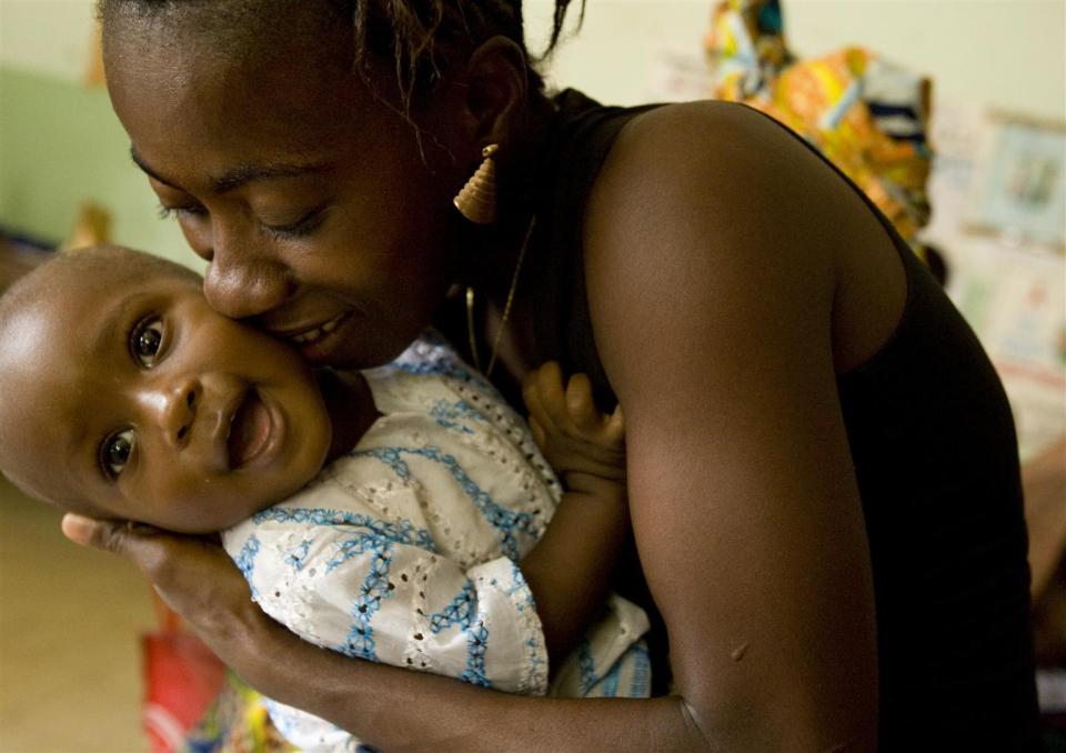A mother kisses her smiling baby as they wait to be seen at the Kono Government Hospital in the town of Koidu, in Kono District, Eastern Province of Sierra Leone in 2010. 