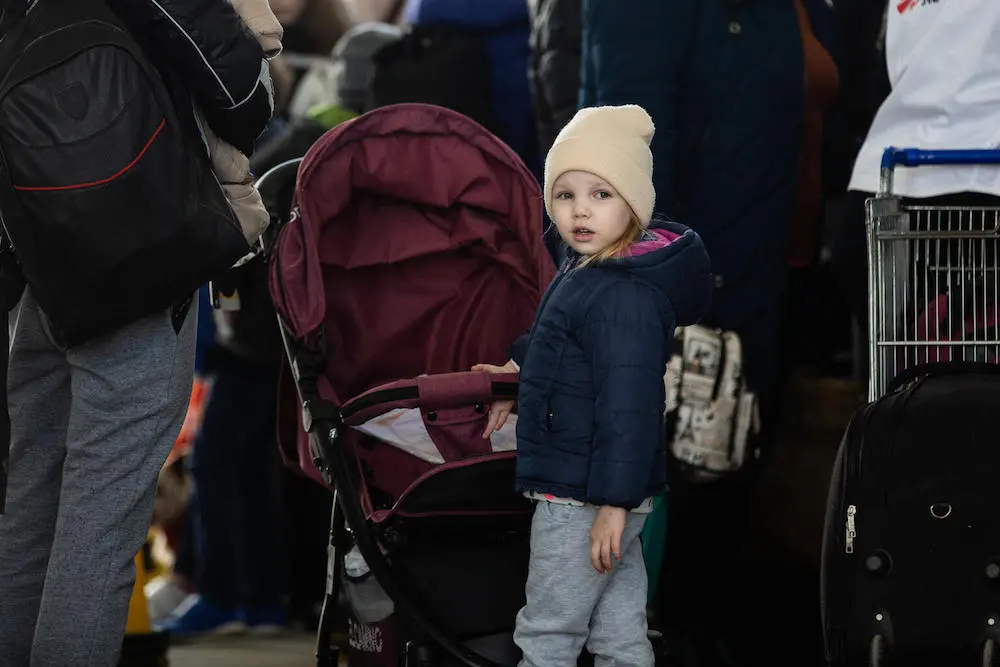 A child refugee from Ukraine stands in line with her mother at the border crossing between Ukraine and Moldova at Palanca on March 24, 2022. 