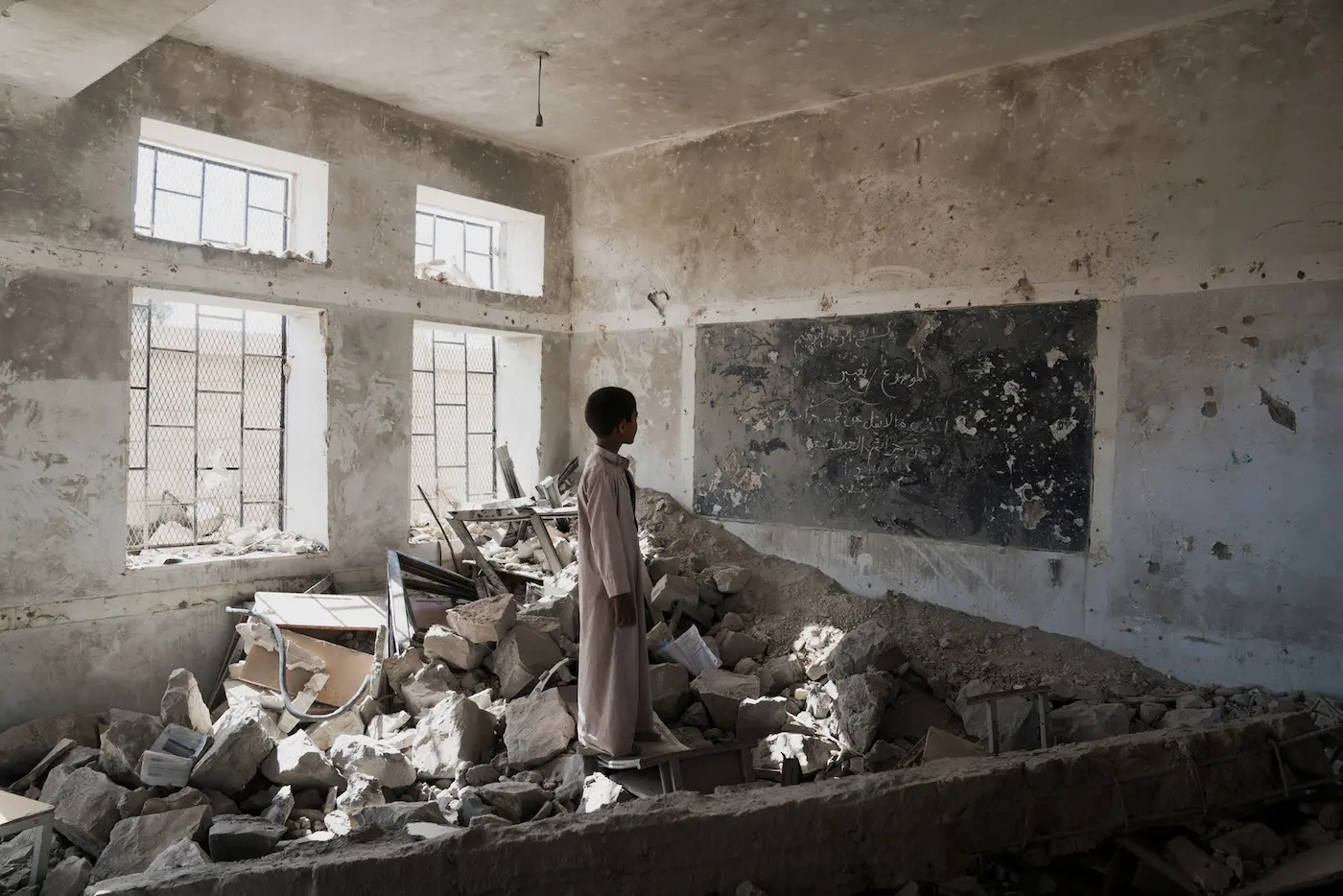A student stands in the ruins of one of his former classrooms at the Aal Okab school in Saada, Saada Governorate, Yemen.