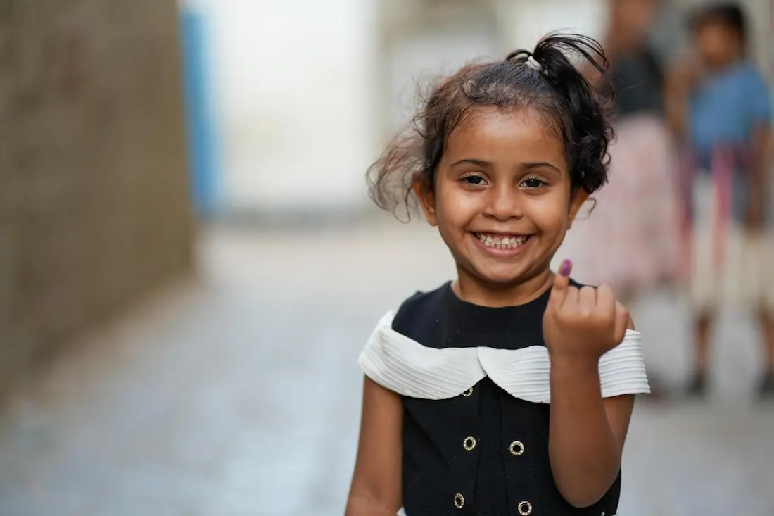 In Aden, Yemen, a young girl beams with pride and joy, displaying her marked finger after being vaccinated against polio as part of an ongoing UNICEF-supported precautionary campaign.