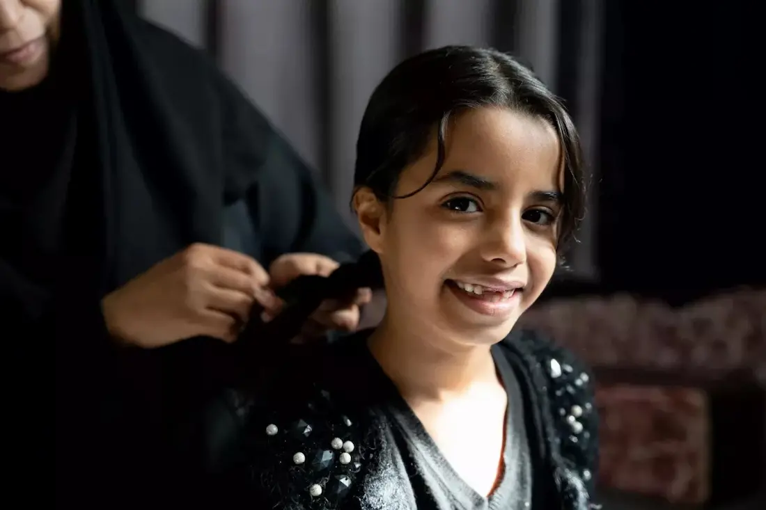 Balqees, 7, gets her hair braided by her mother Khetam. The family lives in Mreighah district, Ma'am governorate, an area suffering from water scarcity.
