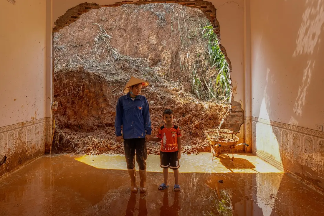 A mother and son stand inside their flooded home in Lao Cai province, Vietnam after Super Typhoon Yagi.