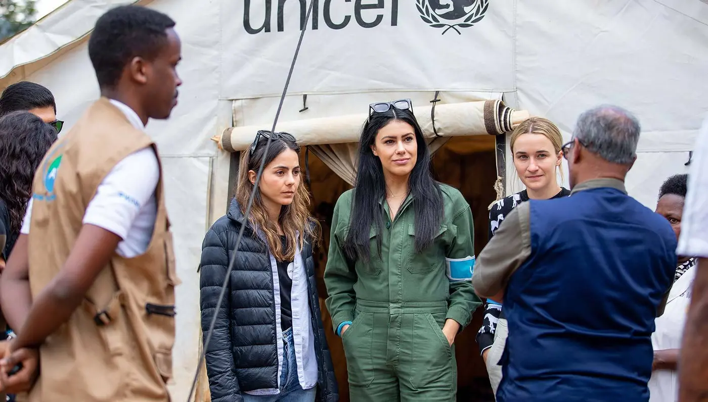 A delegation from UNICEF NextGen visits Rwanda and meets in front of a UNICEF tent to learn and talk about UNICEF programs there.