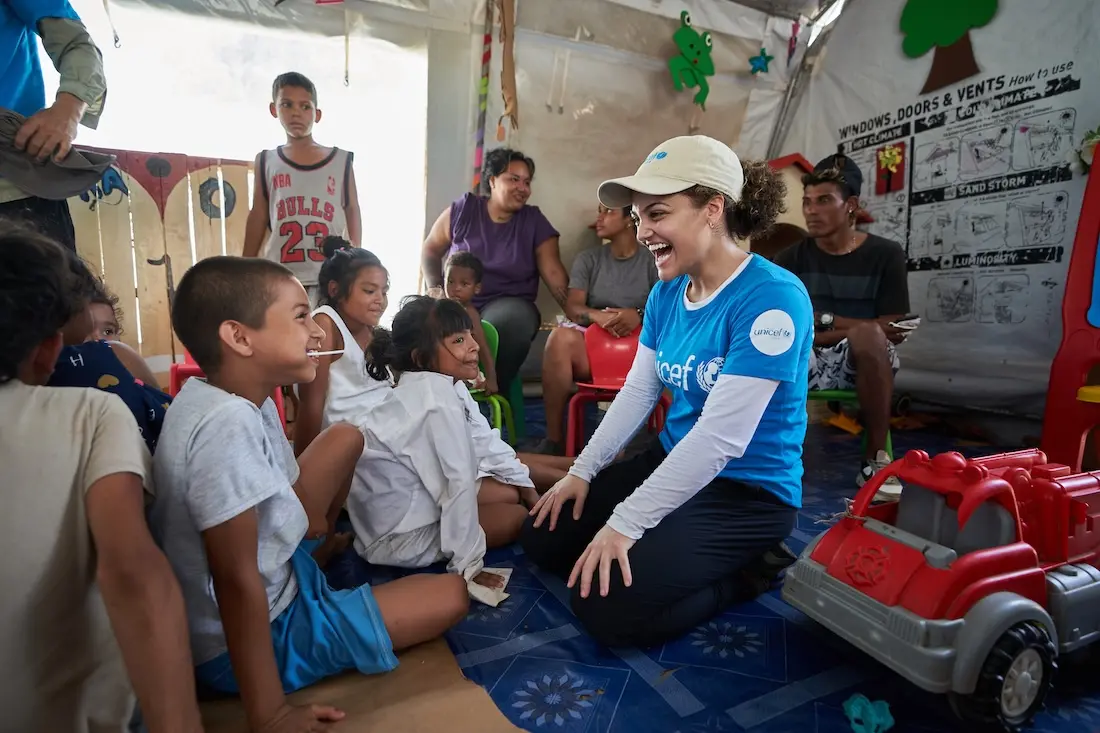 UNICEF Ambassador Laurie Hernandez smiles at a young boy inside a UNICEF-supported child-friendly space providing services to those who arrived in Panama after migrating through the Darién Gap.
