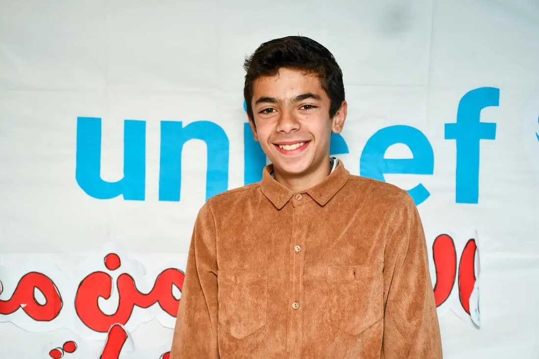 Mohammed, 15, stands in a UNICEF-supported child-friendly space, with a banner partially displaying the UNICEF name behind him, in Bseimeh village, Rural Damascus, on Feb. 2, 2025.