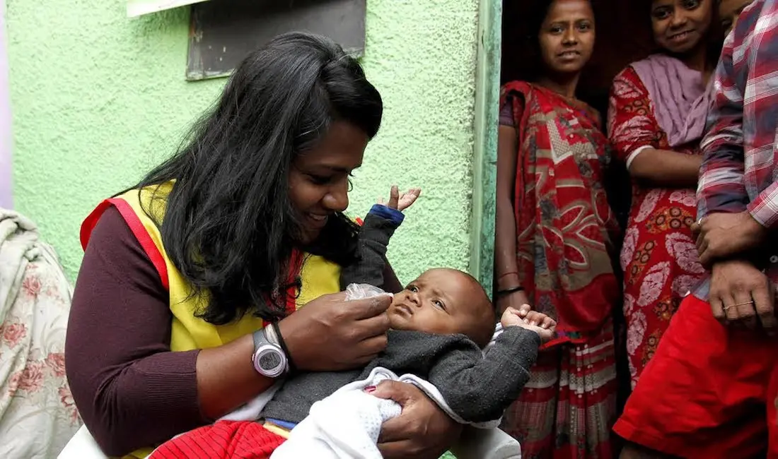 Minda Dentler, a Rotary ambassador, administers the polio vaccine to a child during a national immunization campaign in India.