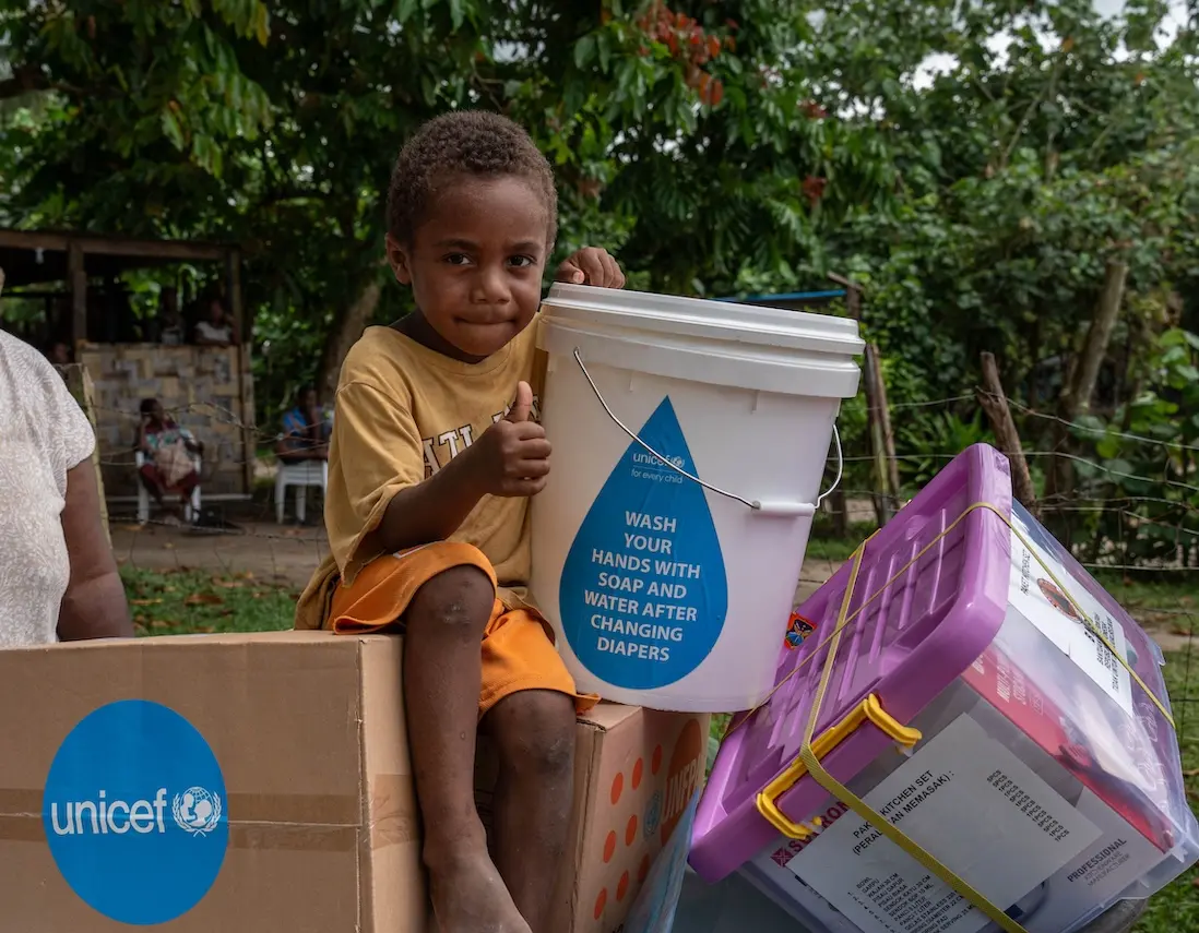 Four-year-old Johnathan sits holding items included in an emergency kit distributed by UNICEF and partners to earthquake-affected families in Erakor Bridge Community in south Efate, Vanuatu, in December 2024.