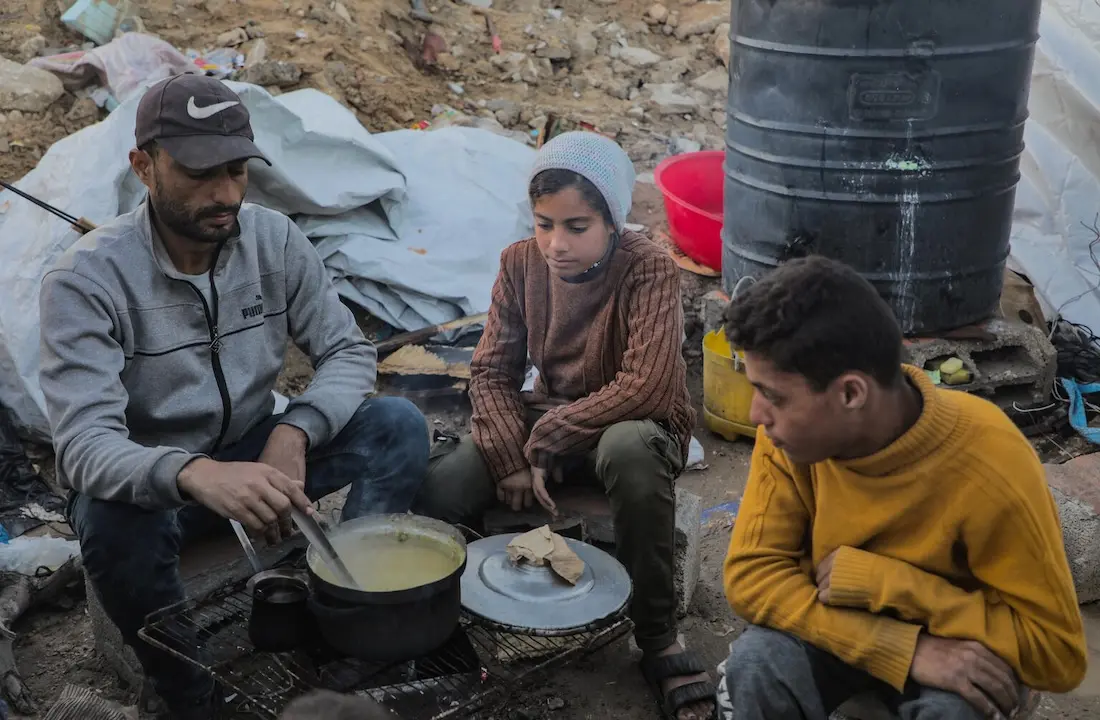 A Palestinian family prepares dinner in a makeshift tent camp on Gaza City's Omar Al Mokhtar Street.