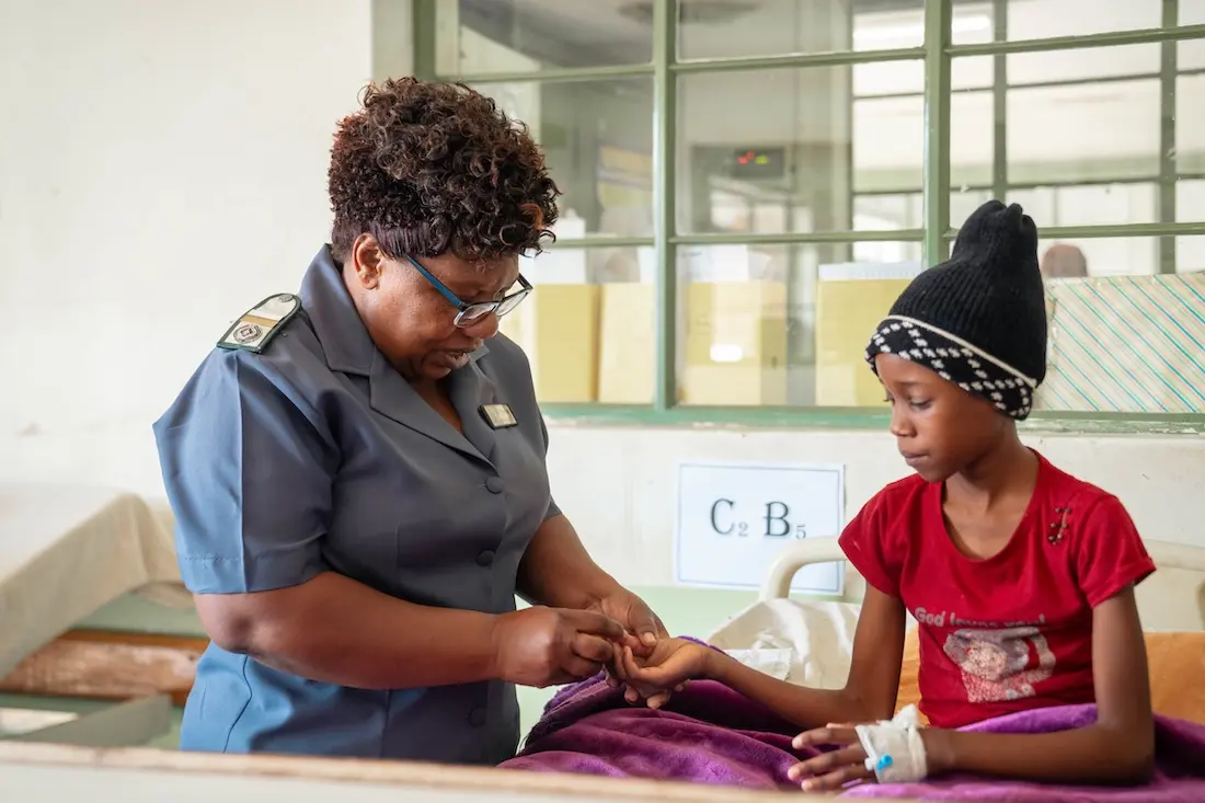 Female nurse touching young girl's finger for blood test