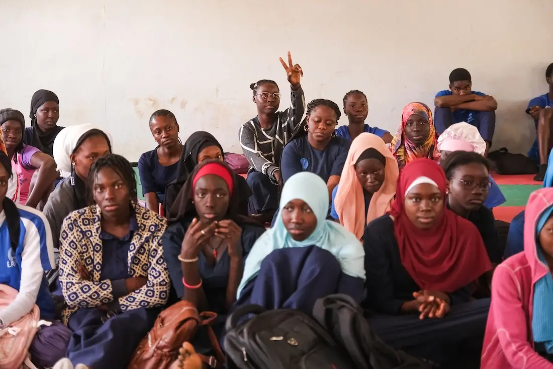 A student raises her hand in the back of a Senegal classroom while participating in a Women’s Teachers Network workshop about menstrual hygiene.