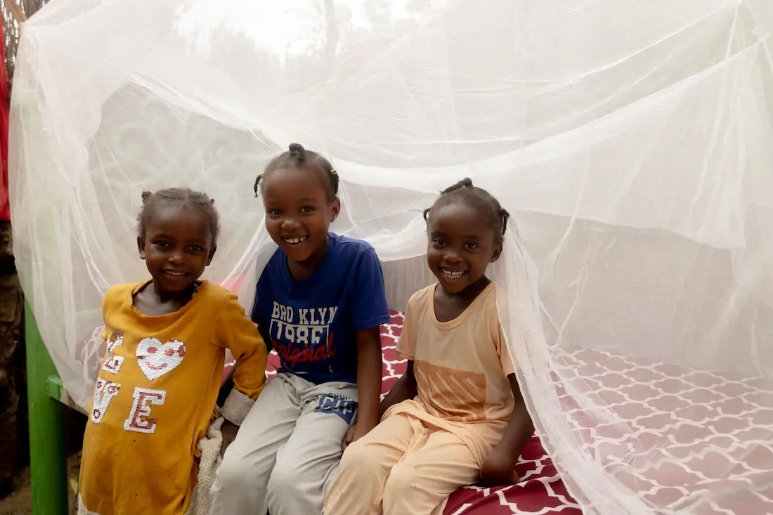 In Blue Nile state, Sudan, girls sit under a bed net provided by UNICEF to prevent malaria, a mosquito-borne illness.