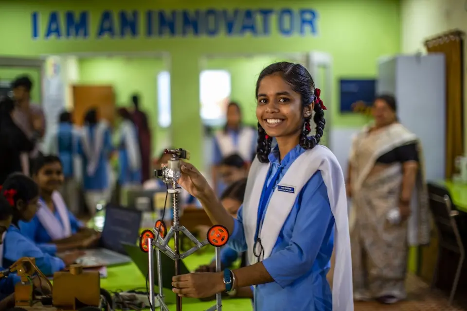 Smiling girl in blue shirt standing in front of table