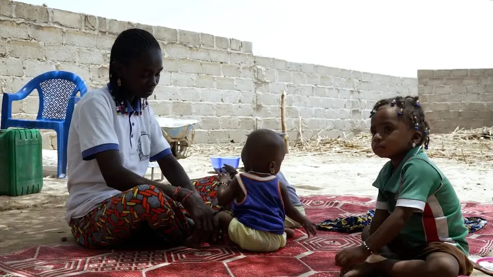 Displaced by violence, a mother and her children sit outside in Burkina Faso.