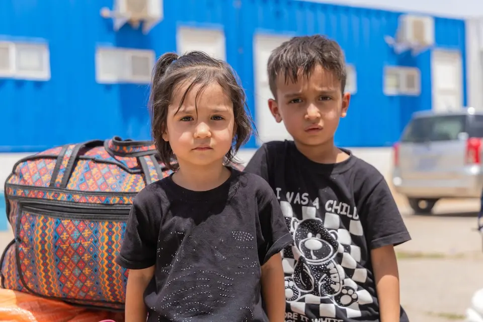 Amir Ali, 5, and Baran, 3, sit next to their family’s belongings in the reception area at the Islam-Qala border crossing, just hours after returning to Afghanistan. 
