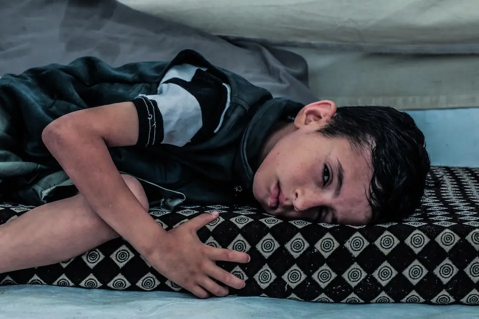 A 7-year-old boy badly injured by shrapnel lies on a mat in the Gaza Strip on June 14, 2025.
