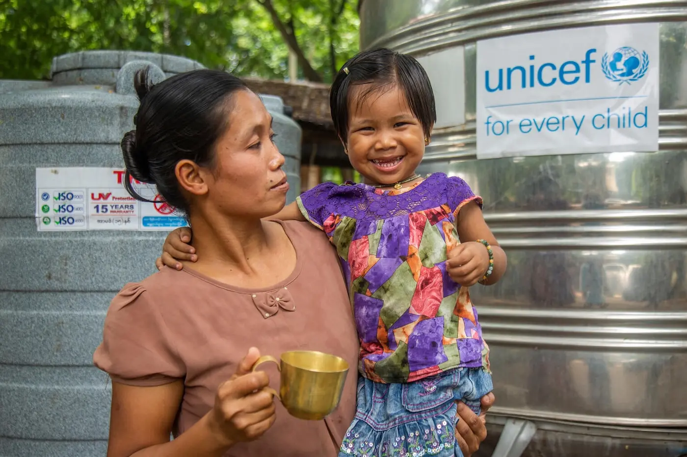 A mother and her 3 year old daughter drink water from a UNICEF-supplied safe water tank in Myanmar following an earthquake