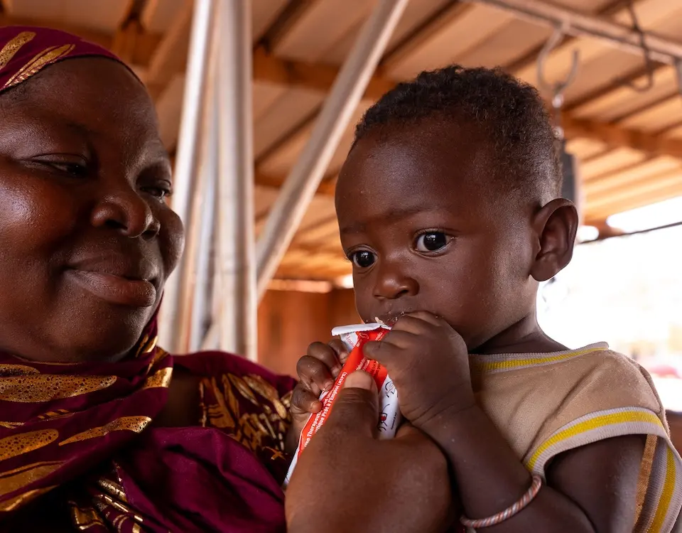 A mother feeds her 11-month-old child a packet of ready-to-use therapeutic food supplied by UNICEF.