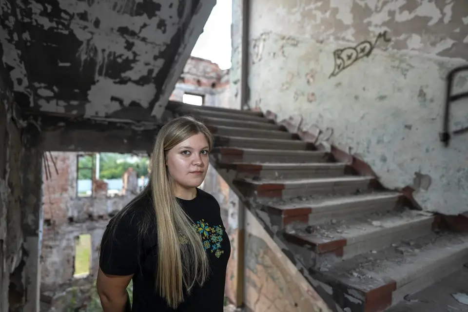 Sofiia, 17, stands in the stairwell of a ruined building in Kharkiv, Ukraine.
