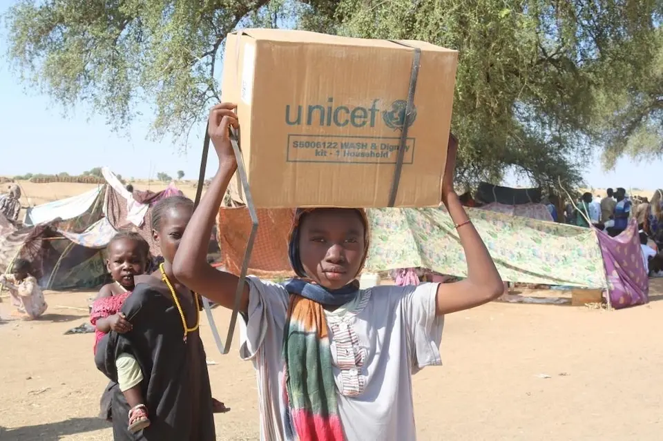A teenage girl in Tawila, Sudan, holds a box containing emergency supplies from UNICEF.