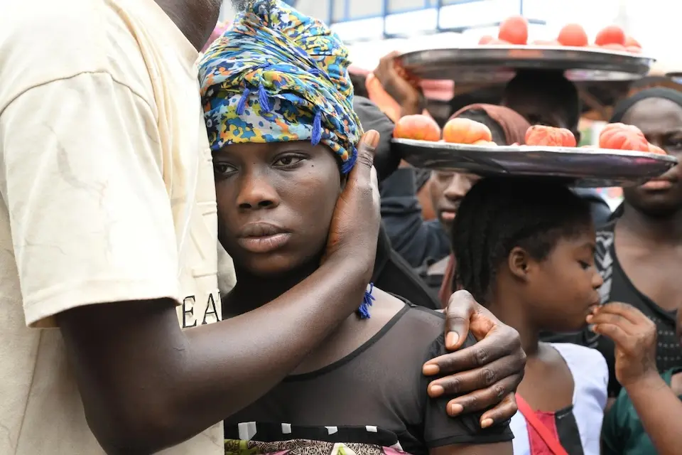 A young girl is held close by a caregiver during a community awareness-raising event about female genital mutilation (FGM) in Conakry, Guinea.