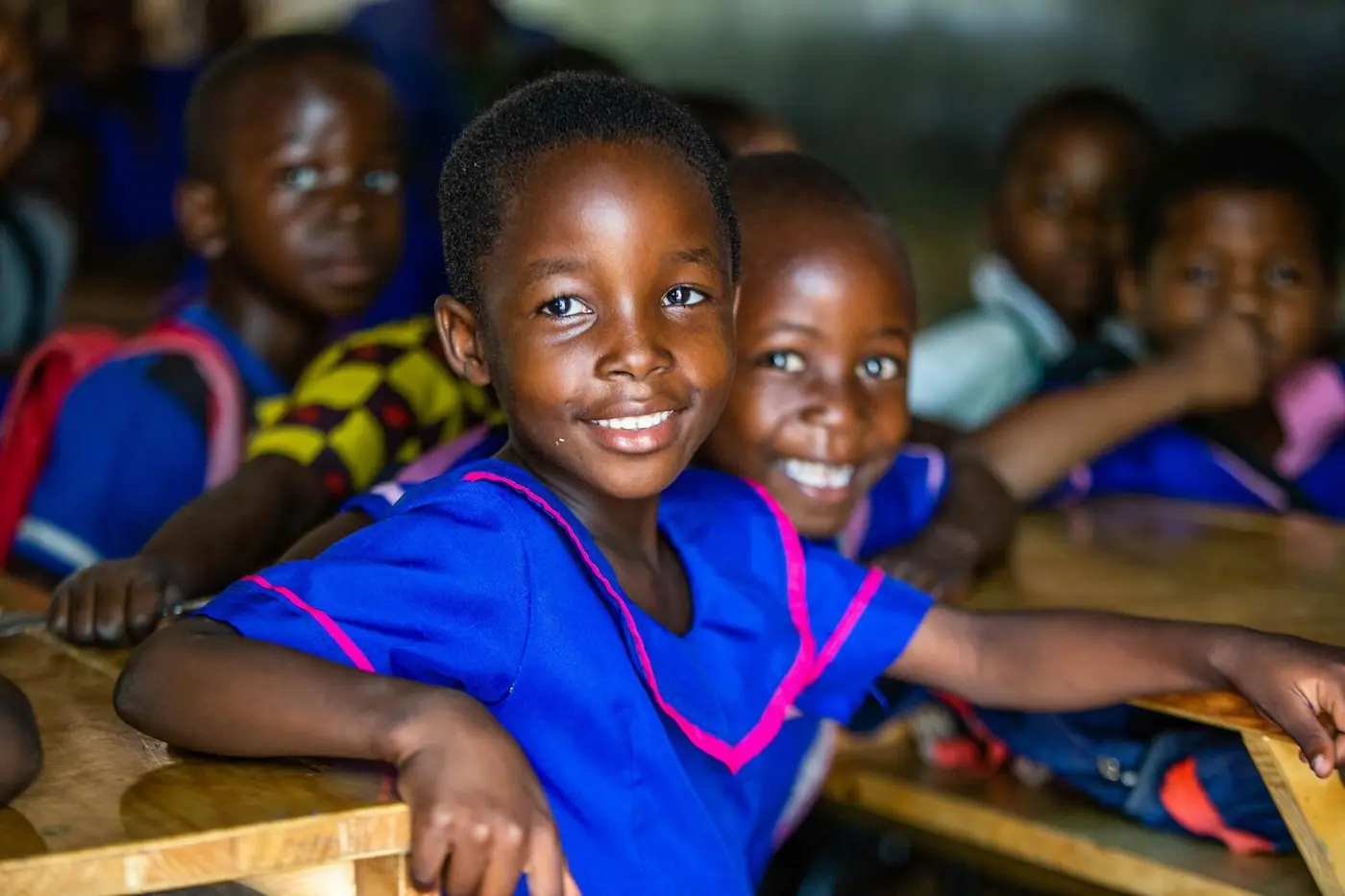 Two girls smile at their school in Malawi, where UNICEF is working to expand access to education