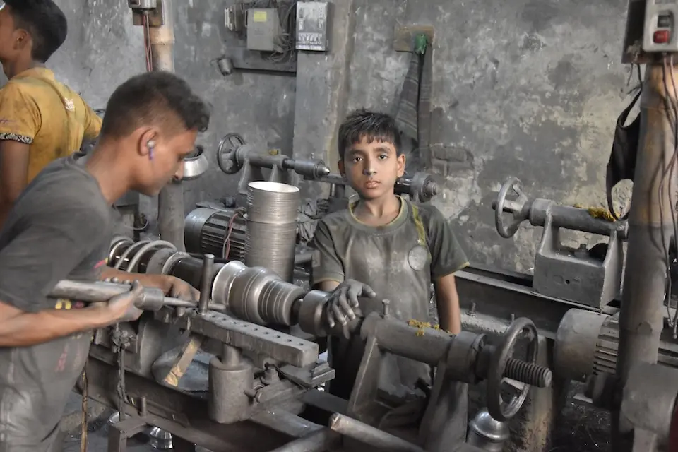 A young boy works in a machine shop when he should be a school.