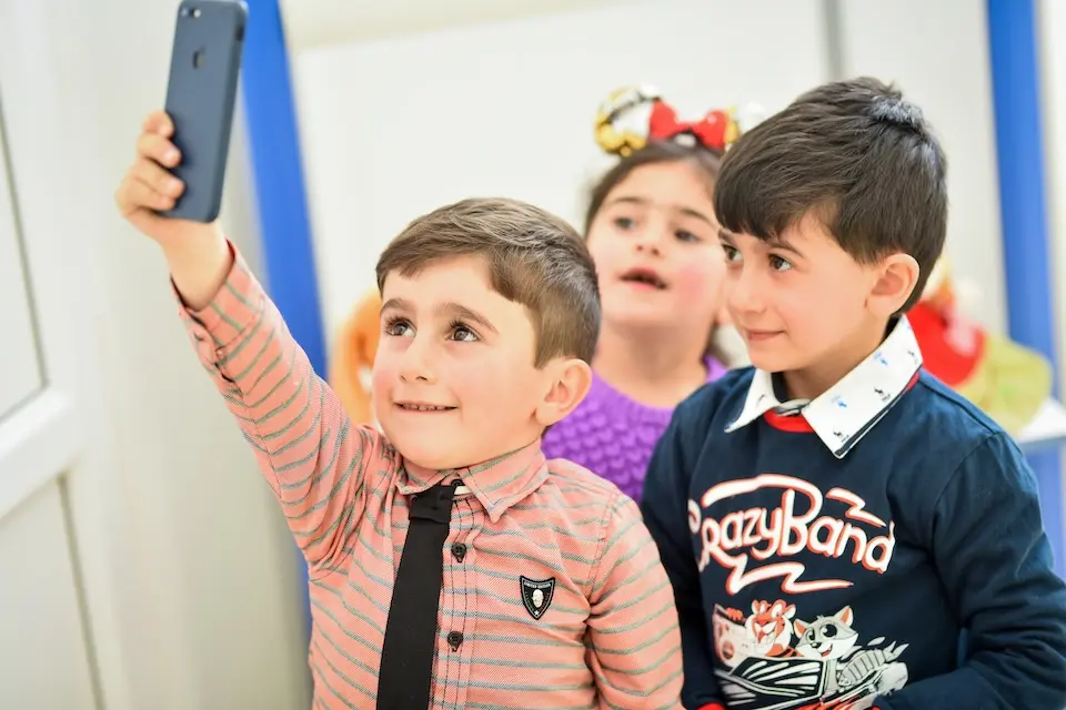 Preschool students share a cell phone in Lori, Armenia.