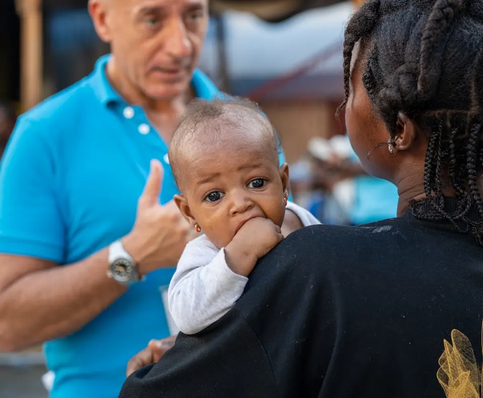 In Haiti following Hurricane Melissa, a UNICEF representative speaks with a mother holding a small child about the needs of impacted families and communities.