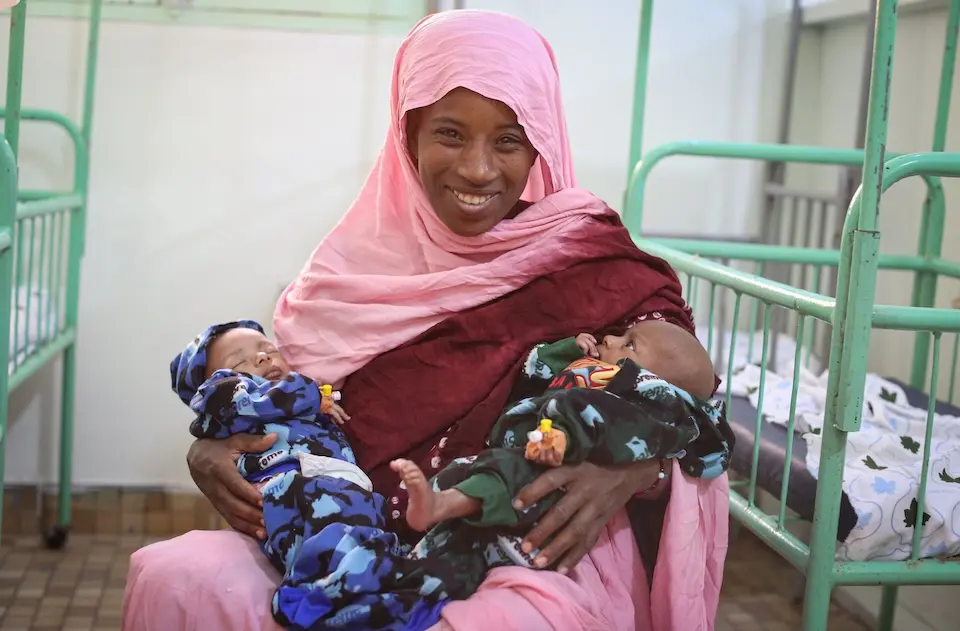 A mother holds her newborn twins at a health clinic that runs on solar power thanks to UNICEF.