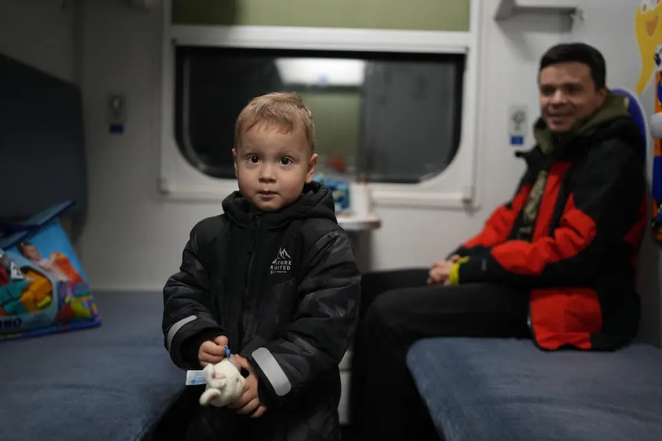 A 2-year-old boy and his father sit in a heated train car used as a warming center for families without heat in  Brovary, Kyiv region, Ukraine. 