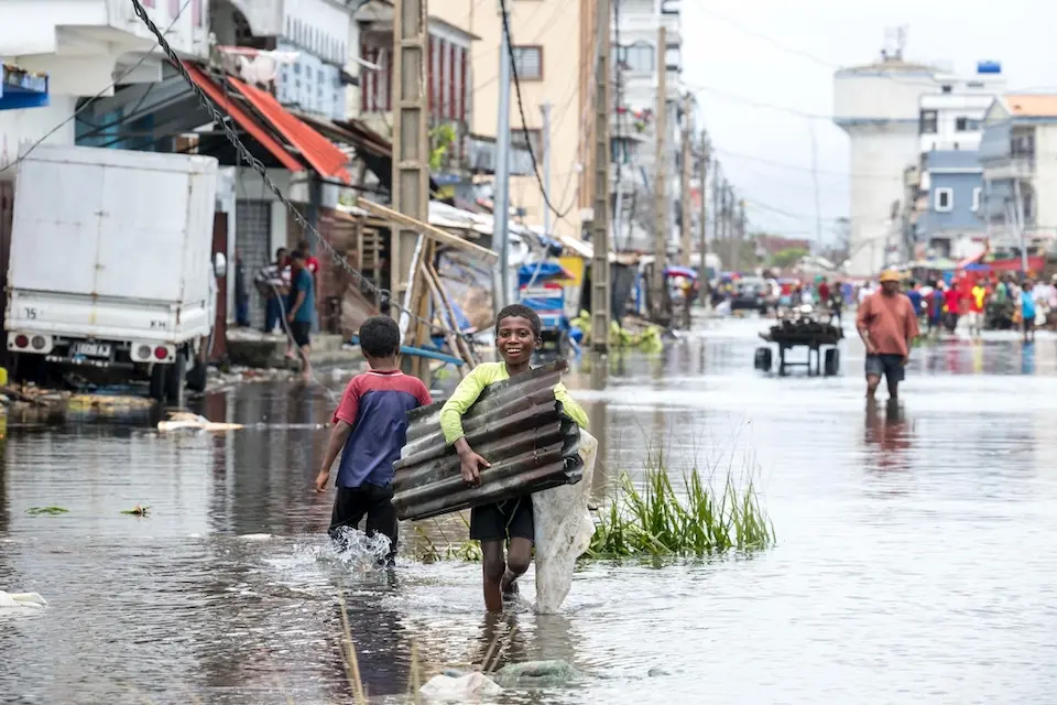 Children in Madagascar walk through flooded streets carrying scrap metal in wake of Cyclone Gezani.