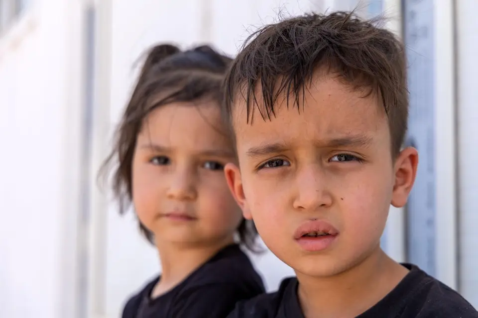 Amir Ali, 5, and Baran, 3, sit next to their family’s belongings in the reception area at the Islam-Qala border crossing, just hours after returning to Afghanistan from Iran.