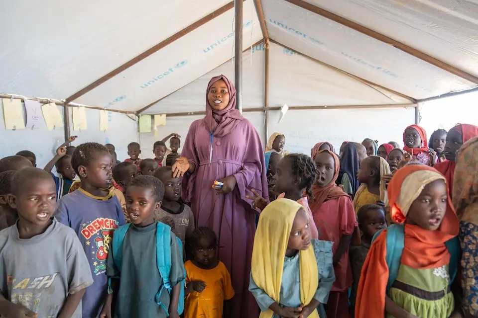 A volunteer stands inside a UNICEF safe learning space full of children in Tawila, North Darfur, Sudan.