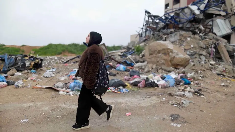 Fatima, 12, walks past the ruins of buildings in her neighborhood in the Gaza Strip.