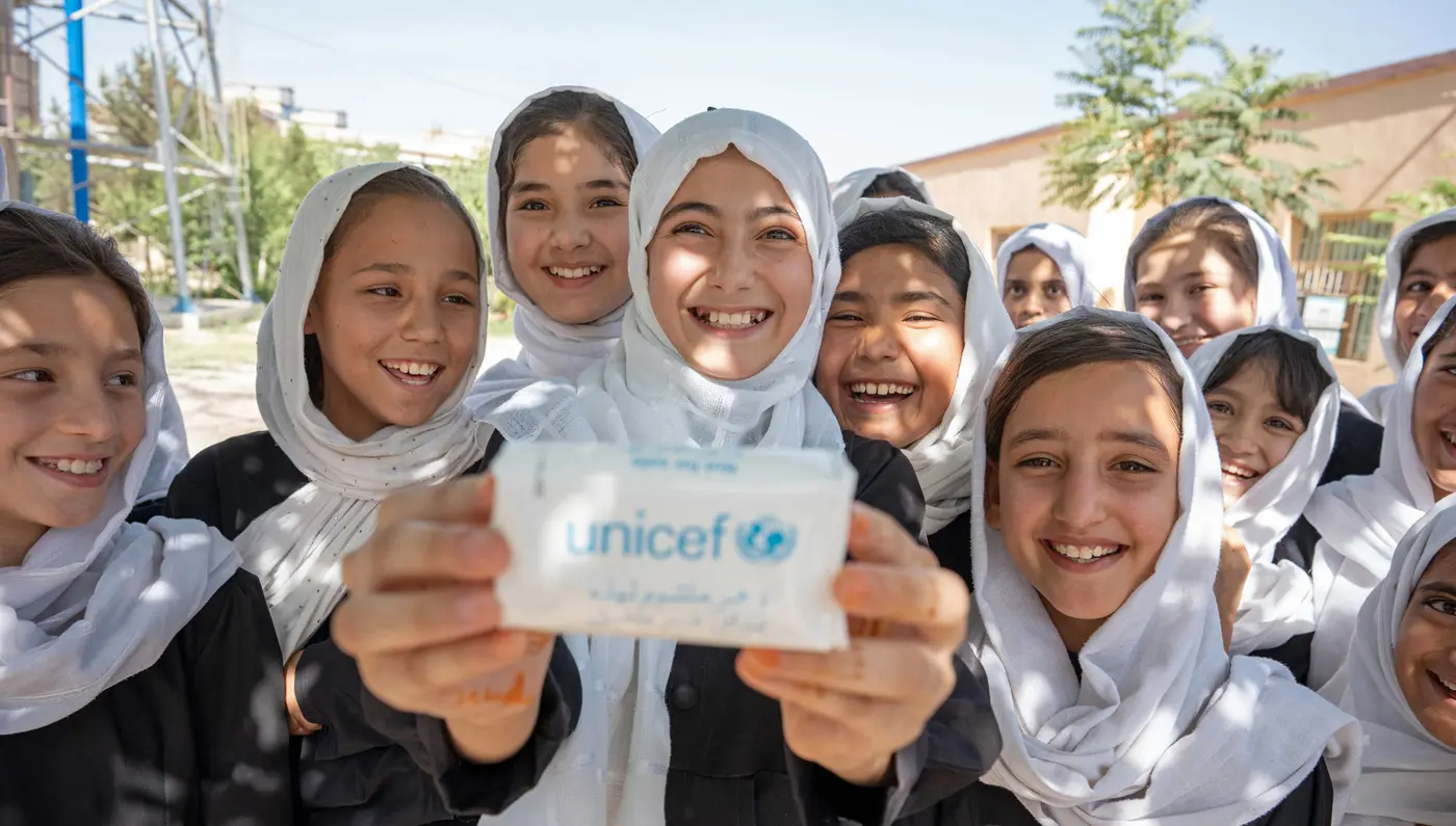 Group of girls smiling and holding a UNICEF item