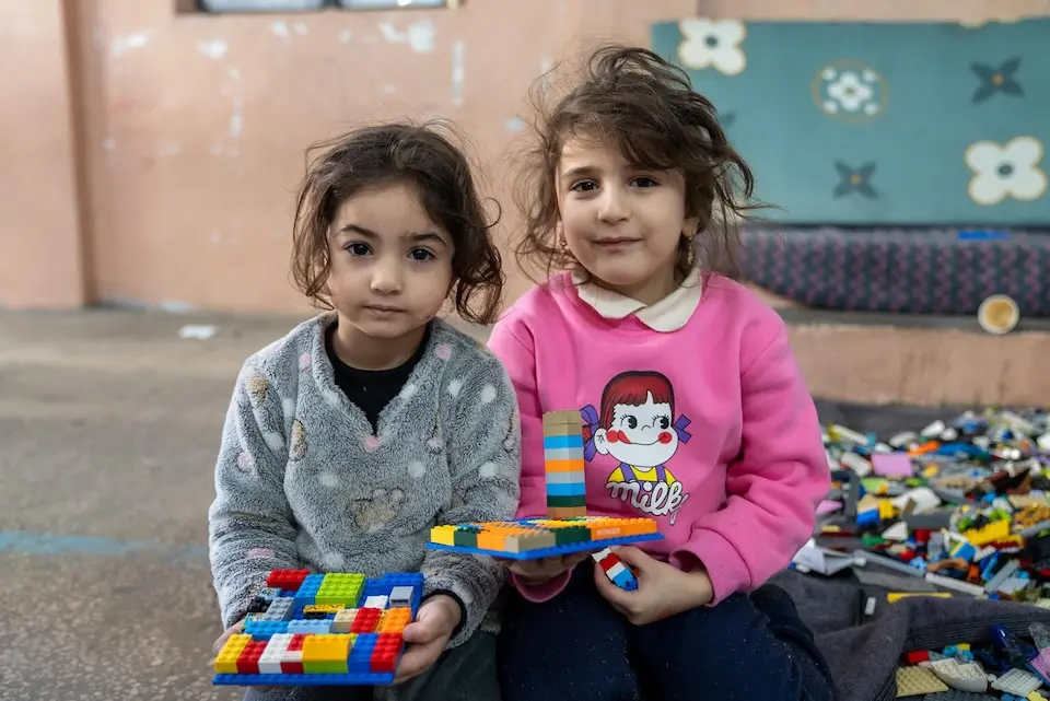 On March 17, 2026, girls play with LEGO bricks at Omar Faroukh school in Beirut, where families displaced by violence are sheltering. 
