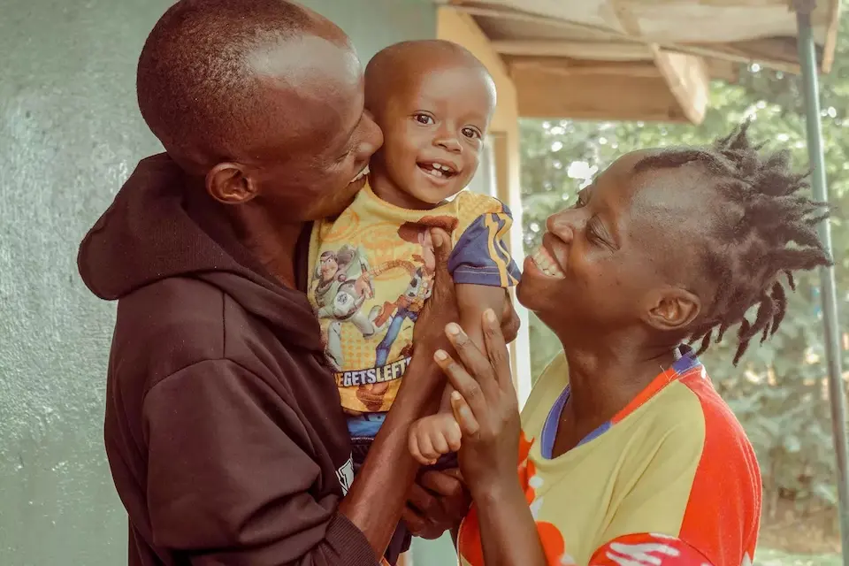 A boy and his parents in Sierra Leone celebrate the child's recovery from severe acute malnutrition.