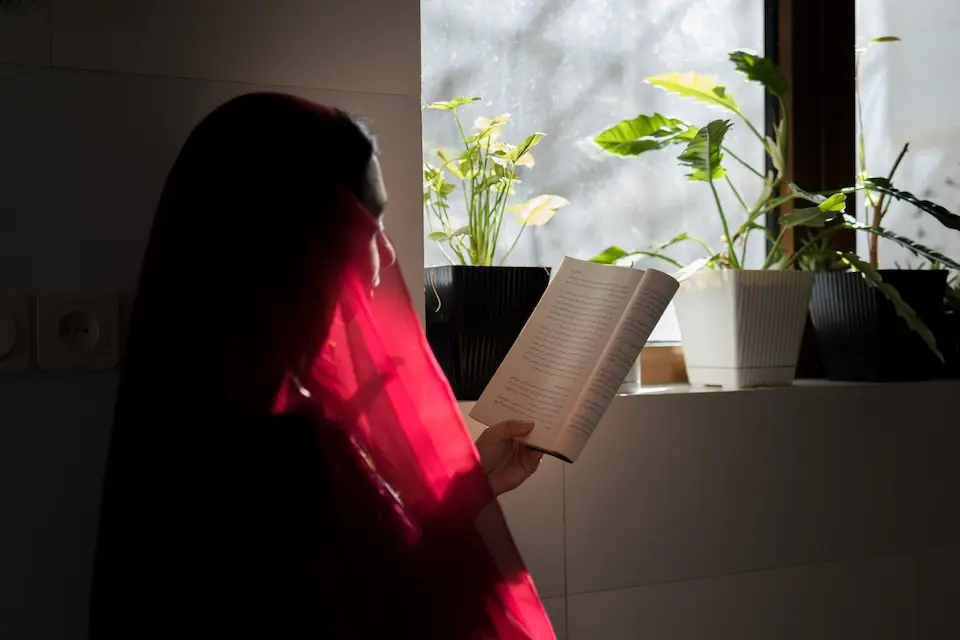 An 18-year-old girl in Afghanistan sits at home reading a book.