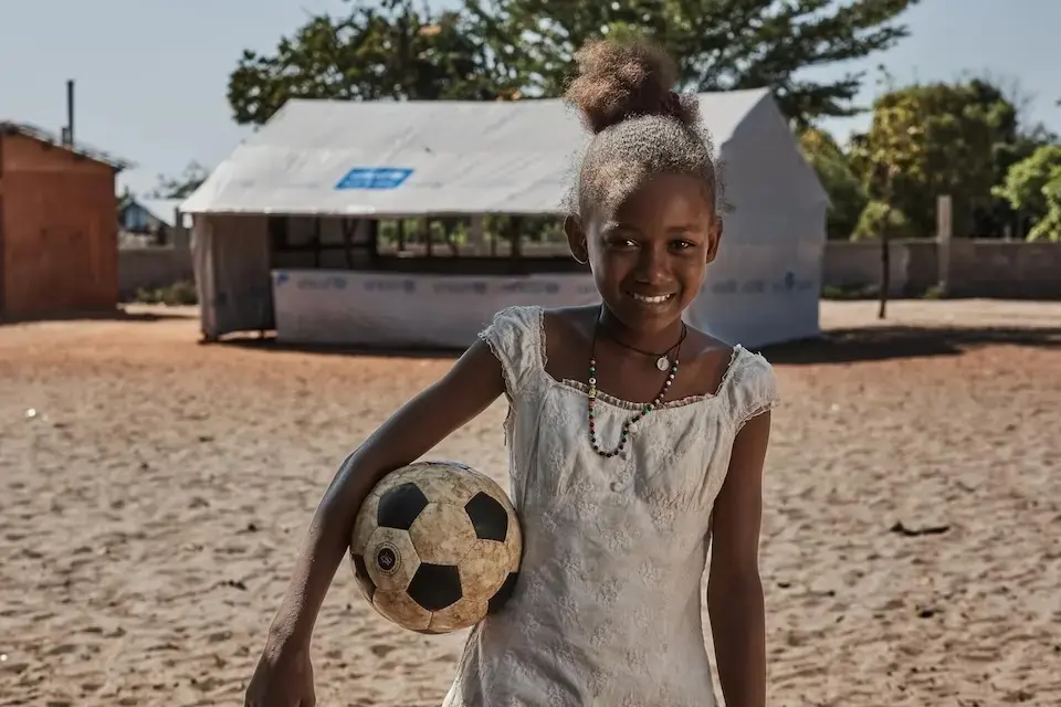 A girl holds a soccer ball outside a UNICEF temporary learning space in Madagascar.
