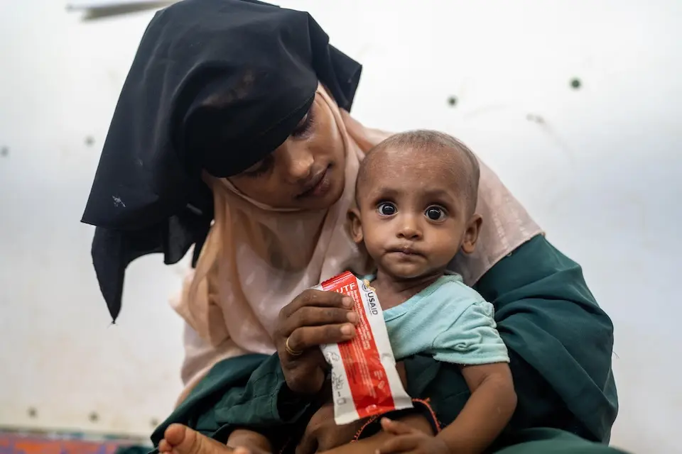 A Rohingya refugee mother feeds her child ready-to-use therapeutic food supplied by UNICEF to treat severe malnutrition.