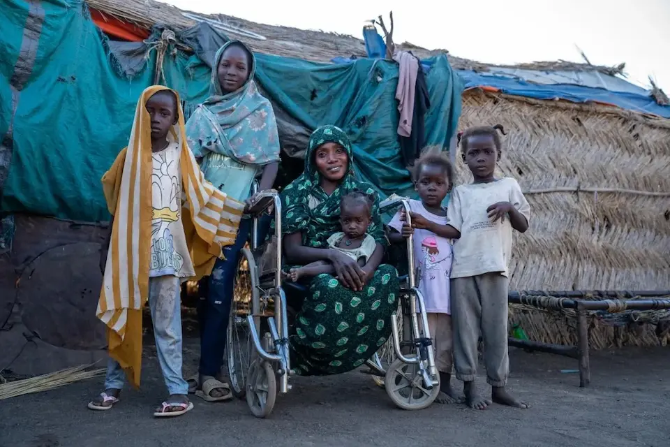 A mother sits in her wheelchair with her five children around her outside the family's home in rural Gedaref, Sudan.