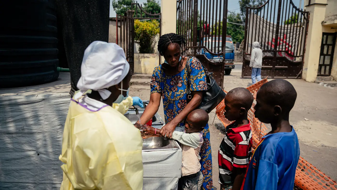 Woman helping children wash their hands in an outdoor sink