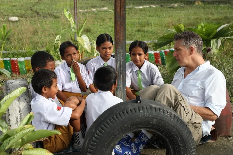 Schoolchildren in Timor-Leste talk with UNICEF spokesperson James Elder, far right. 