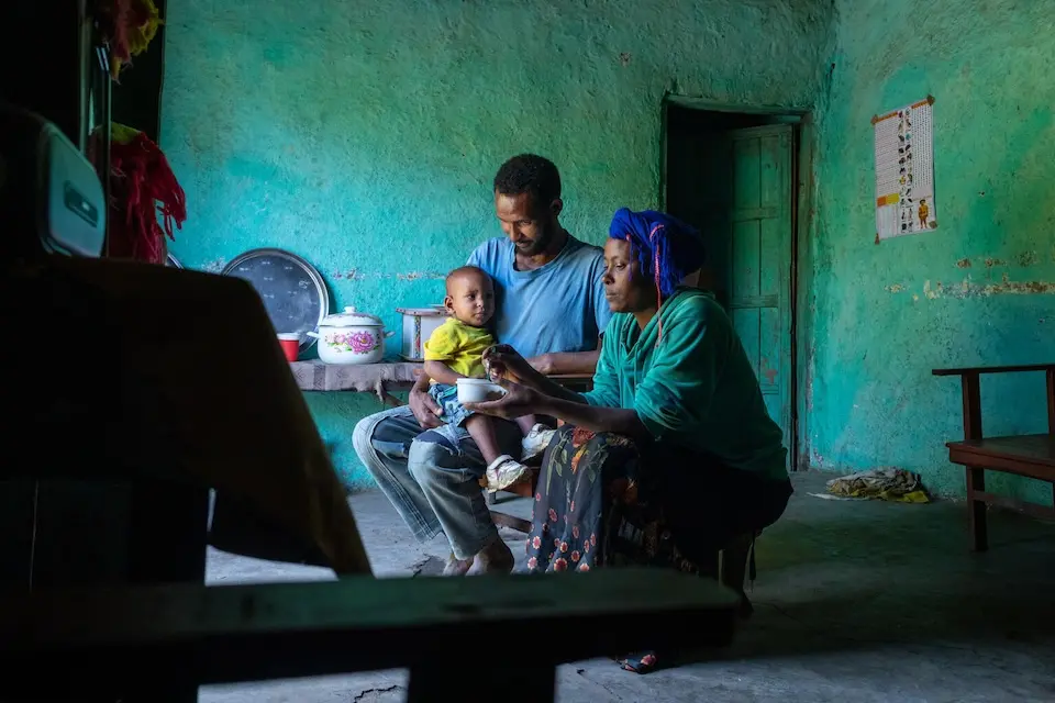 A mother and father at home in Ethiopia with their infant child.