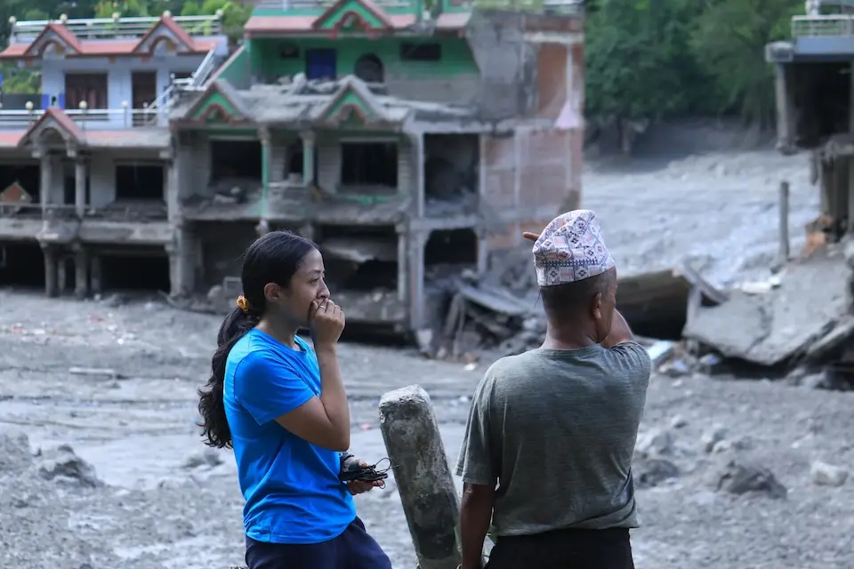 On Aug. 27, 2026, a UNICEF staffer talks to a community member in  Nuwakot District, Bagmati Province, Nepal, as homes and surrounding areas can be seen covered in mud. 