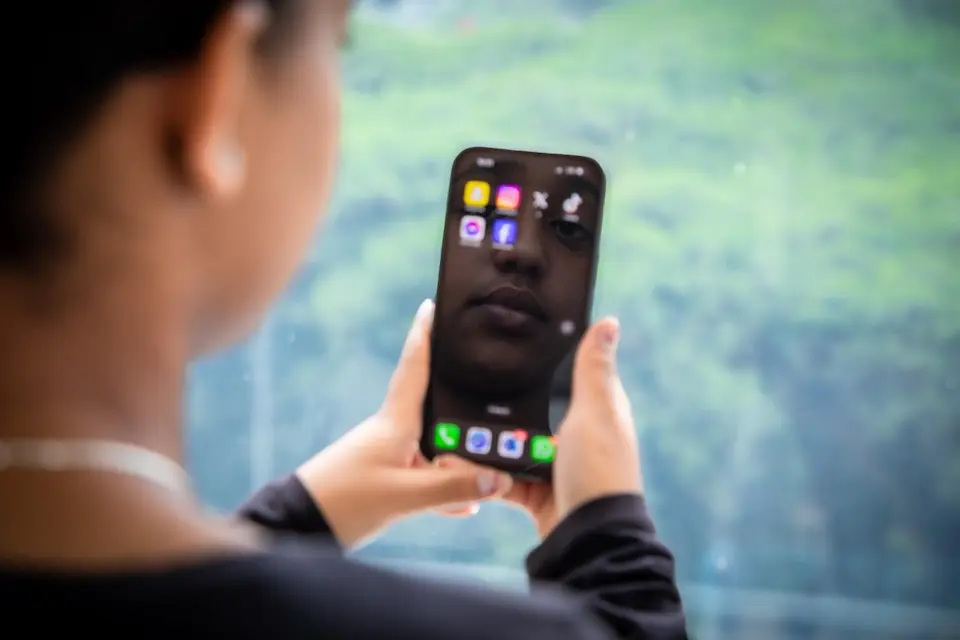 A child looks at her image reflected on a cellphone. 