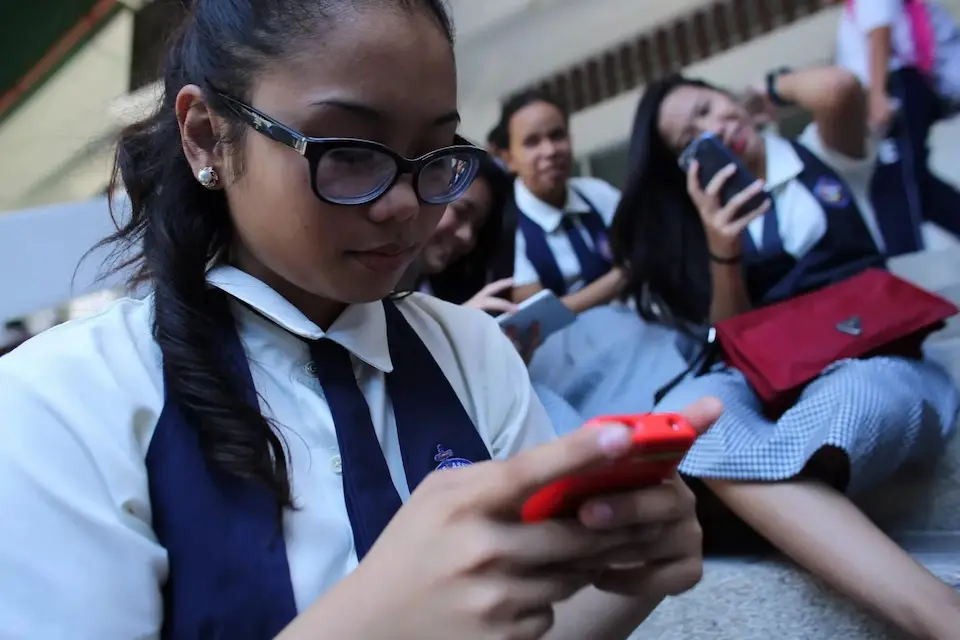 Schoolgirls look at their smartphones.