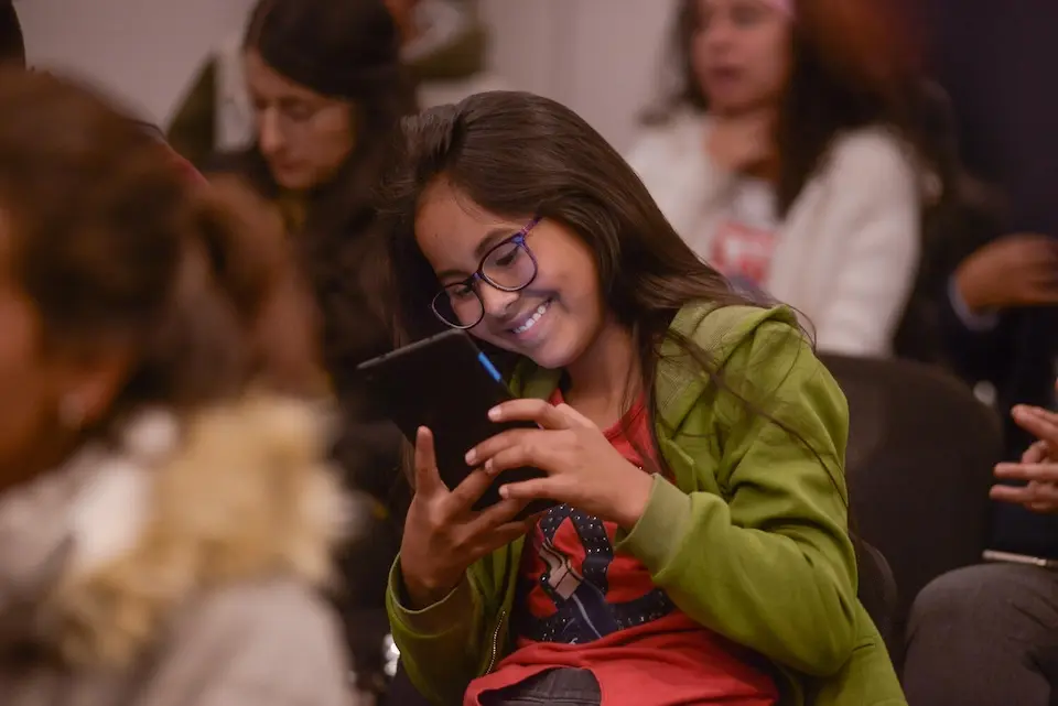 An adolescent girl in Colombia smiles while interacting with a digital device.