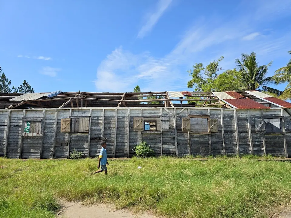 In Madagascar, a boy walks past a classroom destroyed by a cyclone.